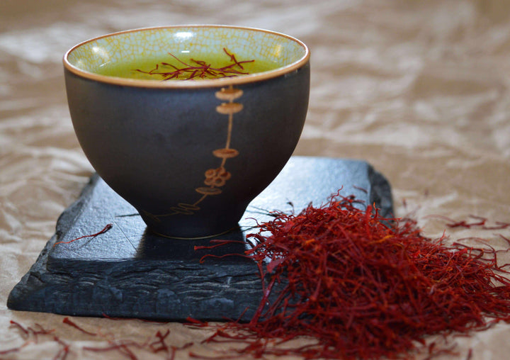 saffron threads in cup with water and saffron on the side