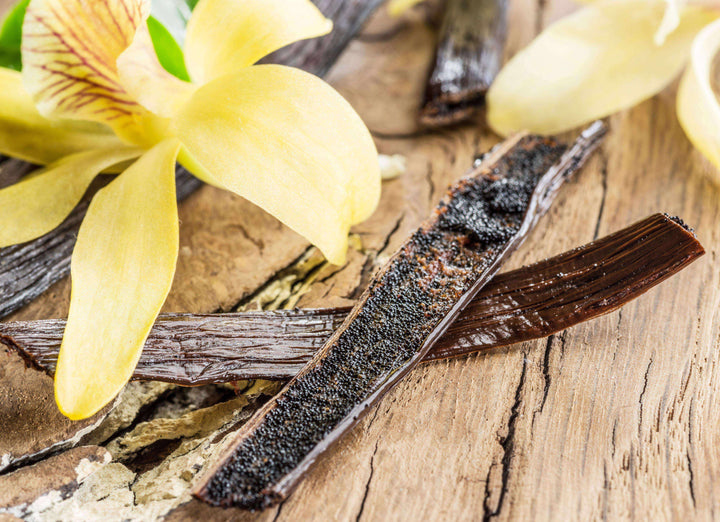 vanilla bean husk split with seeds inside next to orchid