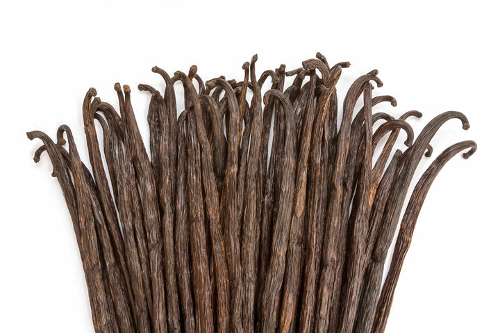 grade b vanilla beans spread out on white background