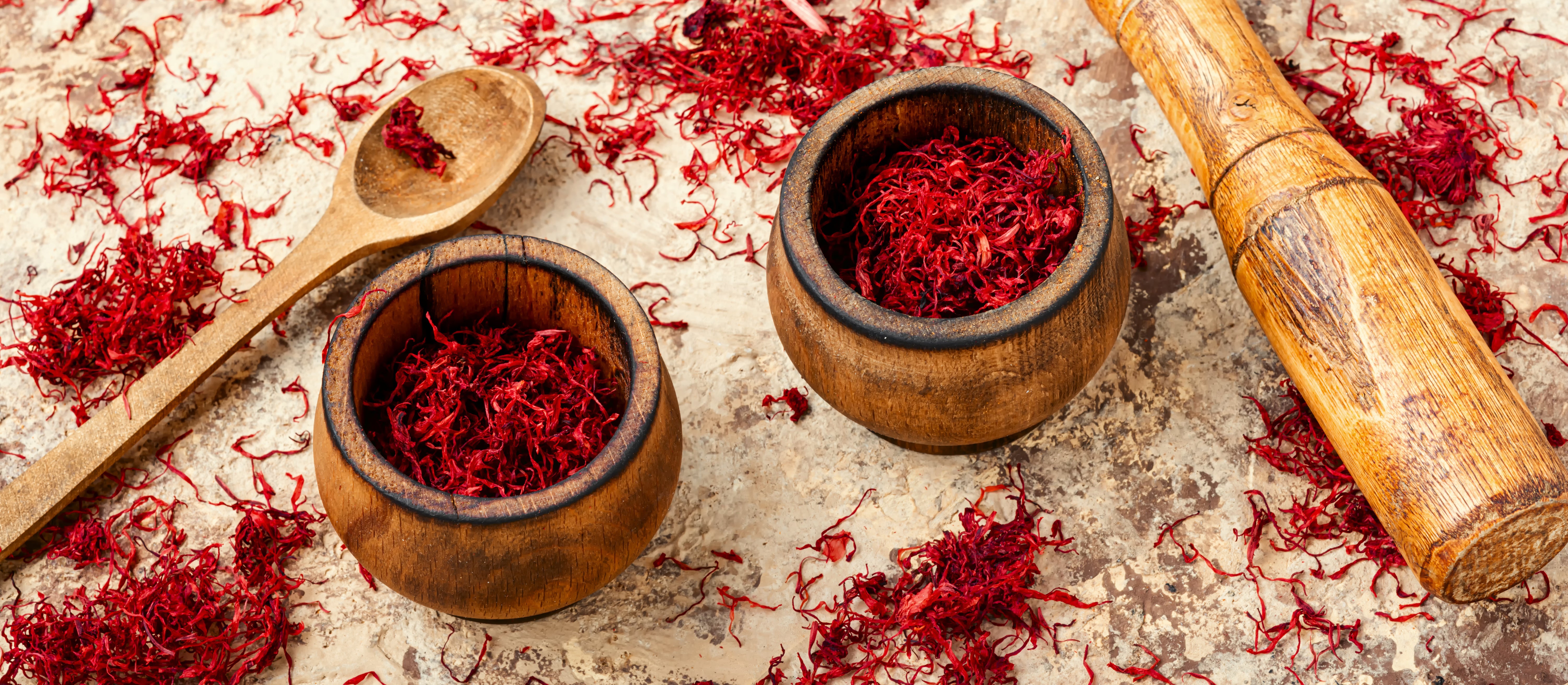 saffron threads in two wooden bowls with wooden spoon and rolling pin