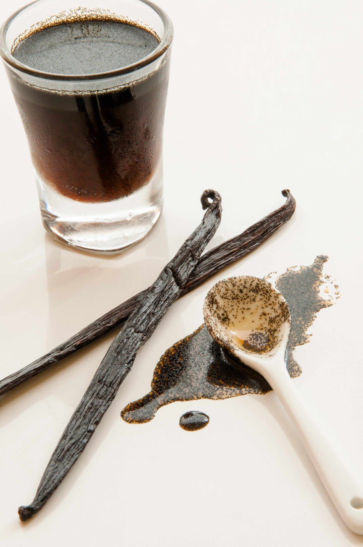 vanilla bean paste in glass with vanilla beans and measuring spoon